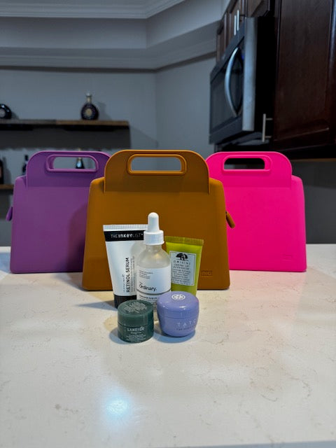 IMAGE OF 3 MEDIUM SIZE IBIG SILICONE MAKEUP BAGS IN FUSCHIA PINK, PURPLE AND BROWN WITH SKINCARE PRODUCTS ARRANGED IN FRONT OF THEM. make up bags / toiletry bags / toiletry / toiletries / make up / make up case /Travel makeup bag / travelbag / travel bags for women / toiletry travel bag / travelbags / cosmetic bags/beauty bag/ makeup / makeup organizer